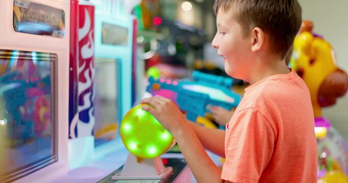 Happy kid playing fun games on arcade machine at an amusement park