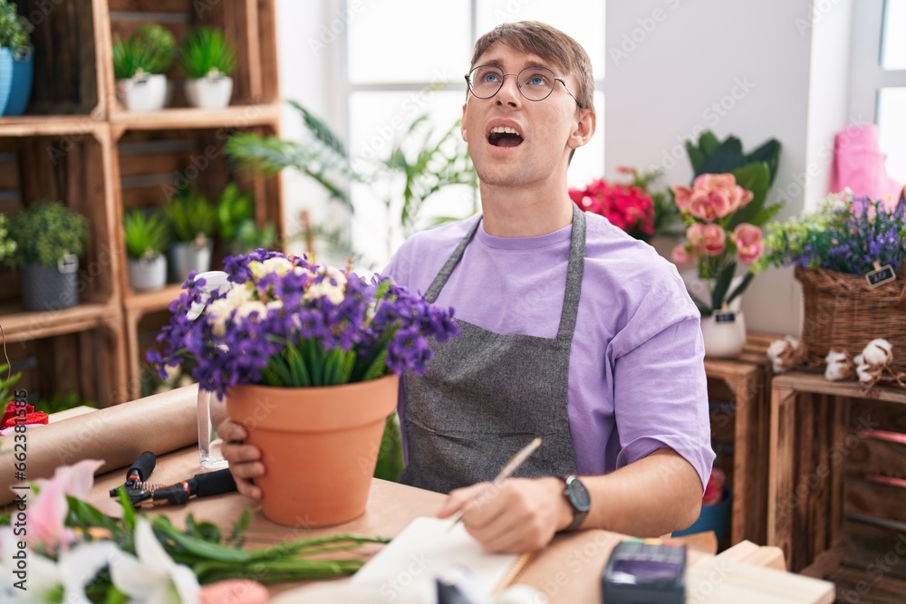 Poster Caucasian blond man working at florist shop angry and mad screaming frustrated and furious, shouting with anger. rage and aggressive concept.