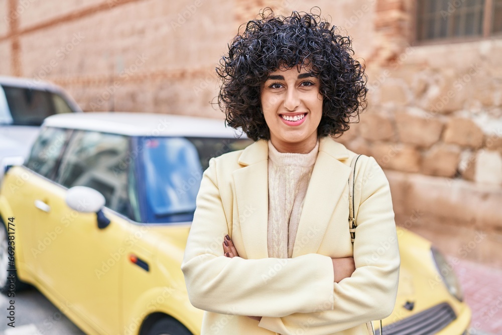 Sticker Young middle east woman excutive smiling confident standing with arms crossed gesture at street