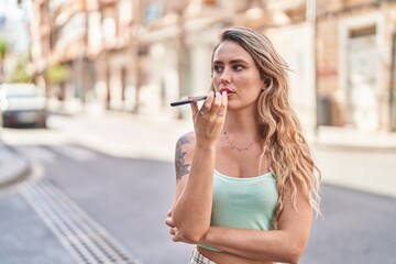 Fototapeta premium Young blonde woman talking on smartphone with serious expression at street