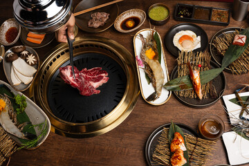 A set of grill food on a wooden table in restaurant.Fresh meat and shrim sliced for grilled menu.Party of friends or family eating dinner on wooden table background.