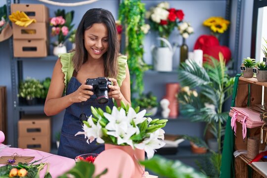 Young hispanic woman florist smiling confident make photo by camera at florist store