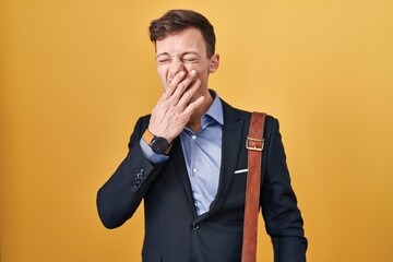 Caucasian business man over yellow background bored yawning tired covering mouth with hand. restless and sleepiness.