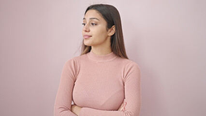 Fototapeta premium Young beautiful hispanic woman standing with serious expression and arms crossed gesture over isolated pink background