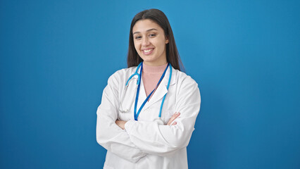 Young beautiful hispanic woman doctor standing with arms crossed gesture saying yes with head over isolated blue background