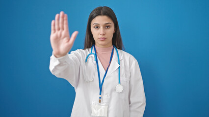 Young beautiful hispanic woman doctor doing stop sign with hand over isolated blue background