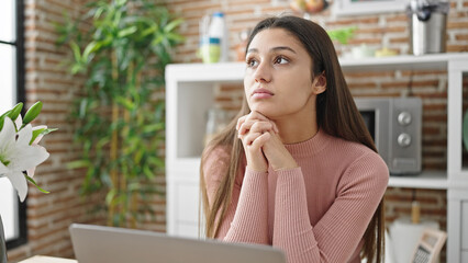 Fototapeta premium Young beautiful hispanic woman using laptop sitting on table at dinning room
