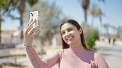 Young beautiful hispanic woman smiling confident making selfie by the smartphone at park