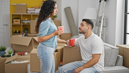 Man and woman couple drinking coffee speaking at new home