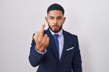 Young hispanic man wearing business suit and tie showing middle finger, impolite and rude fuck off expression