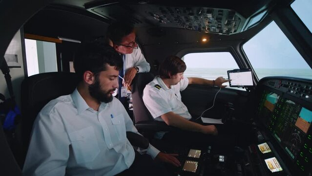 Instructor flight captain observes student pilots while controlling the aircraft panel and preparing for flight in the simulator. Pilots on a flight lesson in a simulator