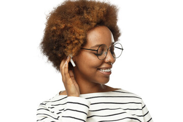 Smiling black woman wearing glasses, touching her afro hair, listening to her favorite music via...