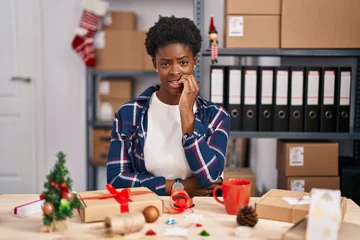 Fotobehang African american woman working at small business doing christmas decoration looking stressed and nervous with hands on mouth biting nails. anxiety problem. © Krakenimages.com