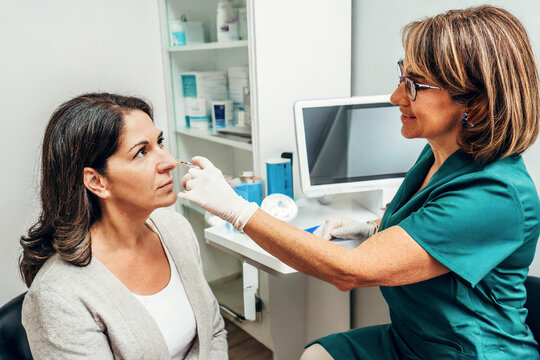 A doctor is examining her patient's face after the cosmetic surgery