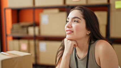 Young beautiful hispanic woman ecommerce business worker smiling confident sitting on table at office