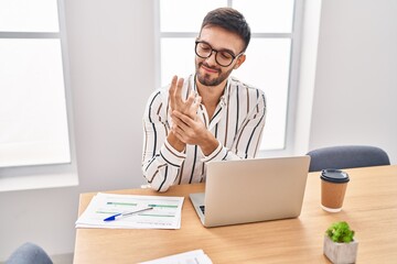 Young hispanic man business worker suffering for wrist pain working at office