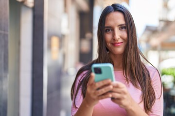 Young beautiful hispanic woman smiling confident using smartphone at street