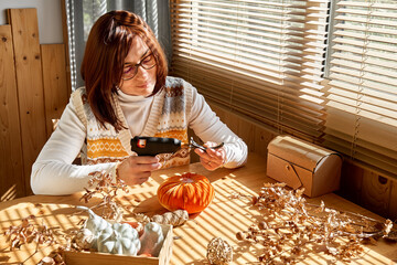 Woman making orange velvet fabric pumpkin. Autumn decoration with handmade textile pumpkin on...