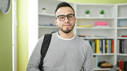 Hispanic man student wearing glasses and backpack at library university