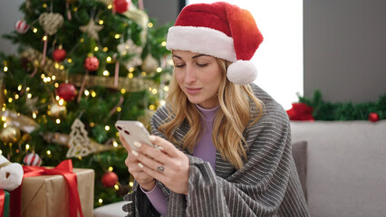 Young beautiful hispanic woman using smartphone celebrating christmas at home