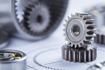 Close up metal gears and bearings. Background with drawings of the mechanism. Industrial mechanism.