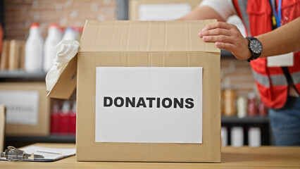 Grey-haired man volunteer packing cardboard box to donate at charity center
