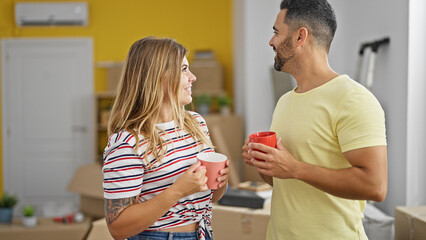 Man and woman couple standing together drinking coffee at new home