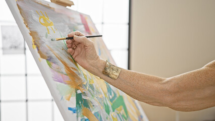 Senior woman artist's hands gracefully drawing on canvas in art studio, a lesson in creativity for mature students at the local academy - obrazy, fototapety, plakaty