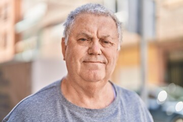 Middle age grey-haired man standing with relaxed expression at street