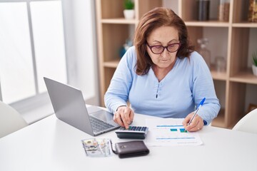 Senior woman using laptop accounting at home