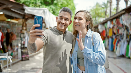 Man and woman couple smiling confident having video call at street market