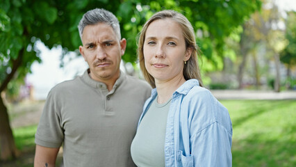Man and woman couple standing together with serious face at park