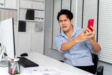 Angry Asian business man being yelled , scolded, complained on the mobile phone for in the office...