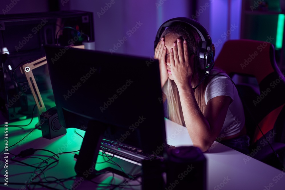 Wall mural Young beautiful hispanic woman streamer stressed using computer at gaming room