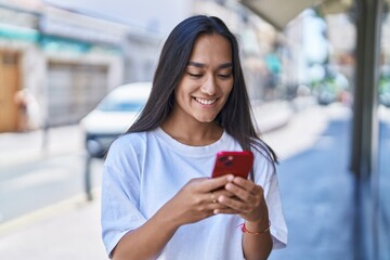 Young beautiful hispanic woman smiling confident using smartphone at street