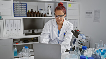 Portrait of a focused young redhead woman scientist, deeply engrossed in her biology research on...