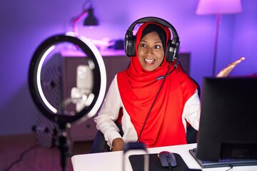 Young indian woman playing video games recording with smartphone celebrating achievement with happy smile and winner expression with raised hand