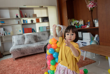 Asian little child having fun kid collecting plastic toy balls