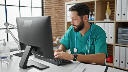 Young hispanic man doctor using computer working at the clinic