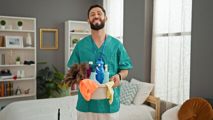 Young hispanic man professional cleaner smiling confident looking watch at bedroom