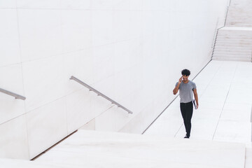 Stylish male with phone in white urban passage