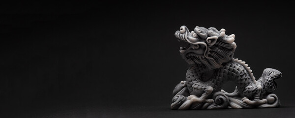 Gray dragon statue on a black background. The symbol of 2024. Happy Chinese New Year.