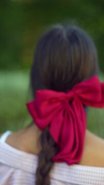 View from behind the young lady with a prominent bow in her hairdo.