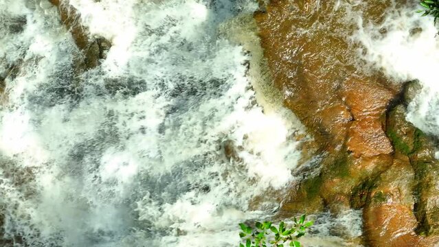 Nature's Masterpiece: Deep in the heart of a pristine rainforest lies a breathtaking waterfall. Its waters flow in elegant layers over ancient rocks, a hidden wonder unveiled from above by drone.
