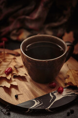 Cozy scene for cold weather with cup of coffee and dried leaves. Autumn composition with hot drink and foliage. Autumnal mood, slow living concept