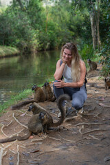 Woman with cute common brown lemurs with orange eyes. Endangered endemic animal in natural forest...