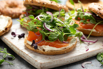 Smoked salmon and soft cheese seeded bagel with pea and purple reddish shoot salad and red onion. Protein packed breakfast concept