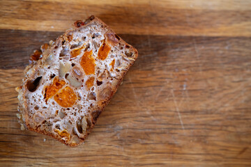 piece of whole grain bread with candied fruits on a wooden background, copy space