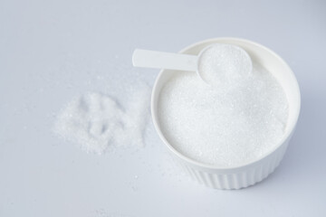 Epsom salts in a bath measuring spoon on a white background. Useful salt for relaxation in the bath. Magnesium salt