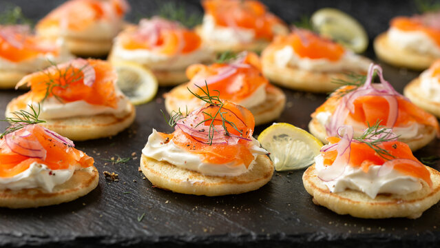 Mini blini pancakes with soft cheese, cold smoked salmon and dill
